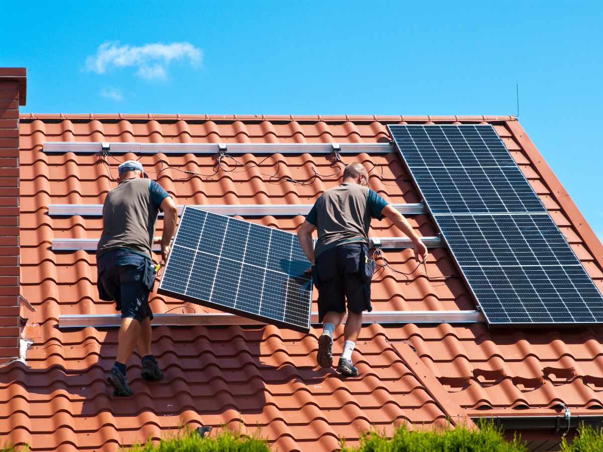 Servicetechniker, die eine Photovoltaikanlage auf einem Dach installieren.